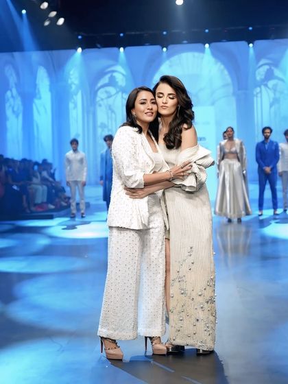 A warm, celebratory hug between Radhika Madan and the designer on stage. This captures the emotion and success of the show.