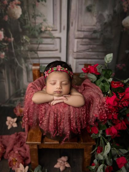 A slightly different crop of the fairytale setup, focusing more on the baby's peaceful pose amidst the rich colors of the flowers.