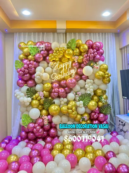 Let's make your birthday pop with a vibrant balloon wall. This full-wall installation uses a mix of metallic pink, gold, and white balloons, accented with tropical leaves and a custom "Happy Birthday" neon sign, creating a perfect backdrop for photos.