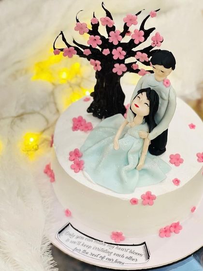 A charming anniversary cake featuring a couple under a cherry blossom tree.
