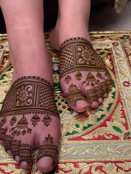A traditional foot mehandi design with full coverage on the front part of the foot. The pattern includes floral blocks and hanging jhumki motifs.