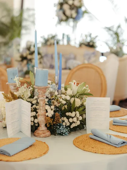 A beautifully composed tablescape with blue candles, a lush floral centerpiece, and custom menus, showcasing a cohesive and elegant design.