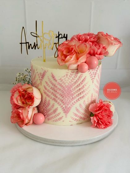 A pretty anniversary cake with a pink leaf stencil pattern and fresh carnations.