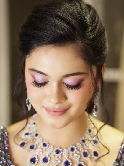 A close-up on the details of this glamorous reception look. The lilac shimmer on the eyes is expertly blended, creating a soft yet impactful effect that complements her jewelry perfectly.