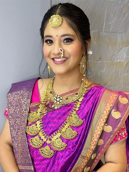 A happy bride showcasing a traditional South Indian temple jewellery set. The antique gold finish and intricate design are perfect for a heritage wedding theme.