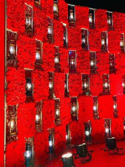 A unique wall decoration for a walkway, featuring panels of red roses with antique-style lanterns placed in alcoves.