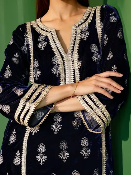 A close up on the sleeve and neckline embroidery of the navy velvet kurta. The silver threadwork stands out beautifully against the dark velvet.