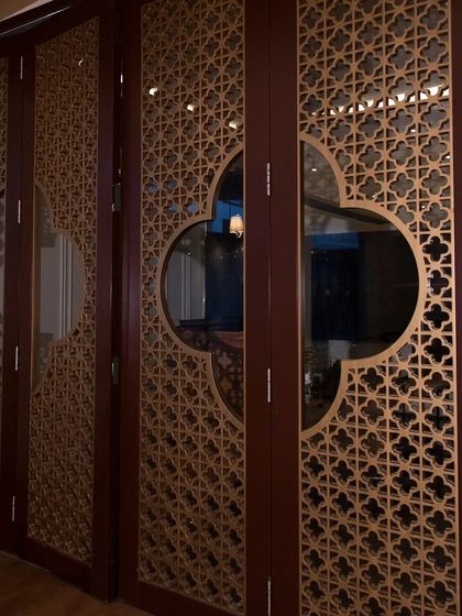 A closer look at the CNC-cut 'jali' doors, showing the precision of the pattern and the elegant gold matte finish.