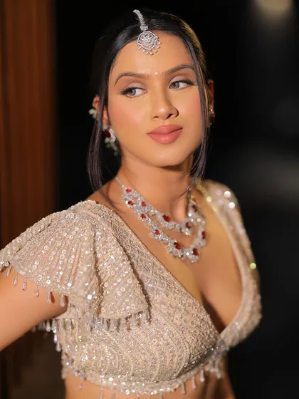 A three-quarter profile view of this soft bridal glam look. It highlights the cheek contour, the jawline, and the elegant hairstyle.