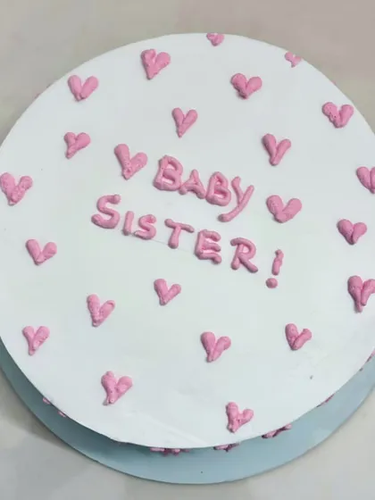 A sprinkle of sweetness and a pop of pink! This simple 'Baby Sister' cake with tiny hearts is perfect for celebrating a special sisterly bond.