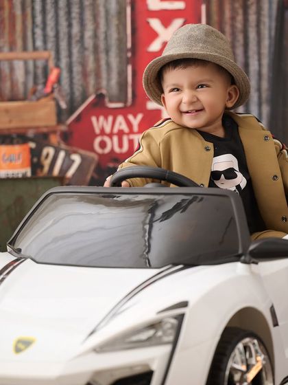 This little driver is ready to hit the road. Our car-themed shoots are always a hit, featuring cool toy cars and garage-style backdrops.