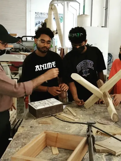 An instructor reviews the progress on a student's project, discussing the joinery and next steps for assembly.