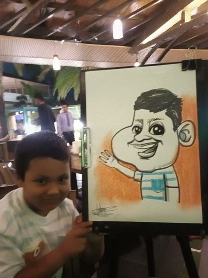 A young boy with his caricature, a fun way to end a family dinner.
