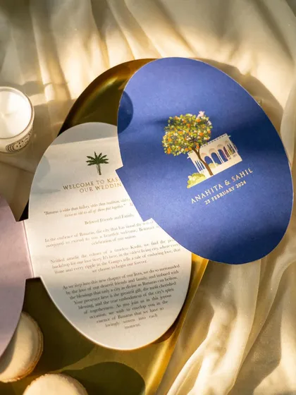 An artistic shot of oval-shaped wedding invitations, with soft, natural light filtering through a sheer curtain. This creates a dreamy and ethereal mood.