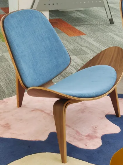 This is a classic shell chair design, known for its unique shape and comfort. The combination of a molded plywood shell and fabric cushions creates an iconic look.