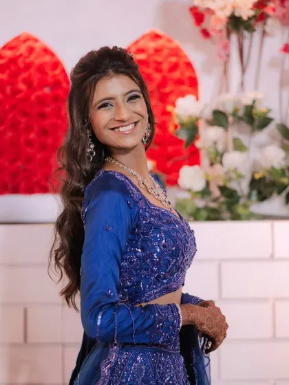 A bright and happy client in a royal blue outfit. Her makeup is fresh and radiant, with a big smile that says it all.