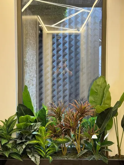 This artificial planter arrangement is perfect for adding a touch of green to a modern hallway. The mix of red and green foliage provides a vibrant contrast against the neutral wall.