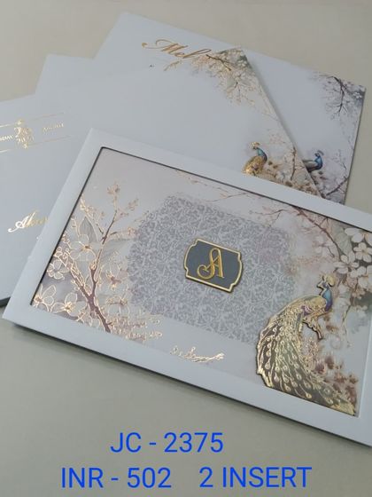 This elegant white framed invitation features a serene winter scene with a golden peacock and a custom initial. The design is modern, artistic, and perfect for a sophisticated wedding.