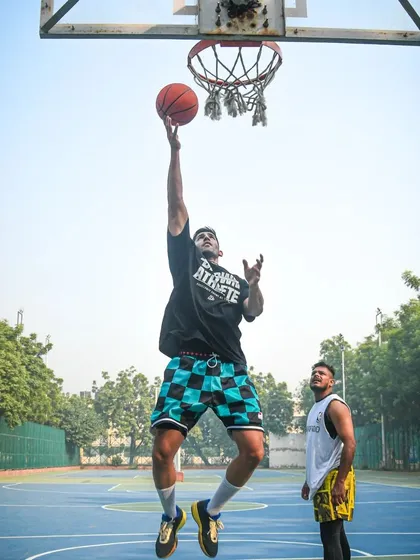 A player flying in for a layup during a group workout. I'm there watching, ready to give feedback.
