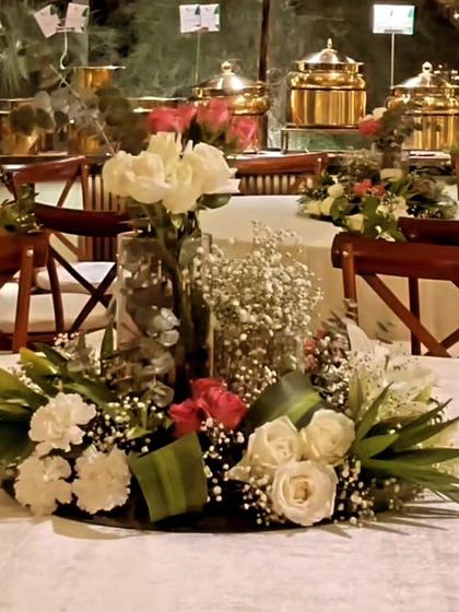 A close-up of a table centerpiece I created for an evening event. This arrangement includes white and pink roses, baby's breath, and green foliage in a clear glass vase.