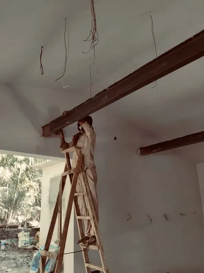 A worker carefully positions a steel I-beam, a crucial step in reinforcing the ceiling structure of an old building. This modern intervention provides necessary structural support while remaining hidden to preserve the historical aesthetic.