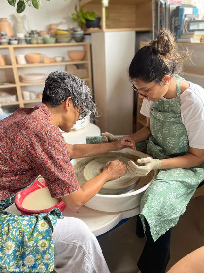 A moment of hands on guidance, as I help a student refine her technique on the pottery wheel, ensuring she feels supported in her learning journey.