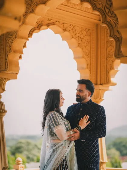 A pre-wedding portrait framed by a beautiful sandstone arch, highlighting architectural elements to create a grand and elegant composition.
