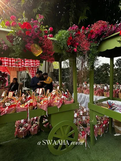 A beautifully styled cart overflowing with flowers and picnic basket favors, adding to the charming, rustic theme of the baby shower.