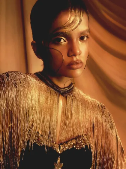 A beautiful close-up of the fringed outfit and the complementary gold makeup, highlighting the textures of the look.