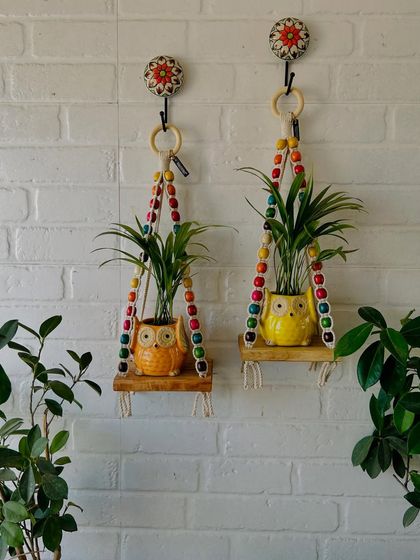 Another beautiful example of our beaded wall shelves, this time paired with our ceramic owl planters in orange and yellow. The colorful beads and natural wood are perfect for adding a playful and rustic touch to your home.