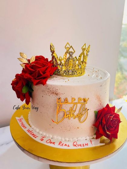 Where elegance meets indulgence. A regal cake with a golden crown and deep red roses.