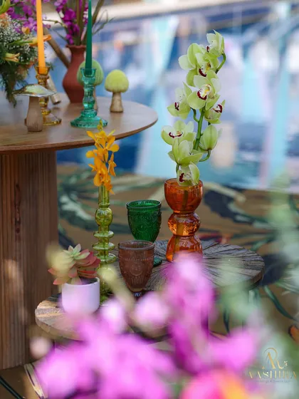 A close-up of the whimsical table decor, featuring colorful mushroom figures, orchids, and vibrant glassware.