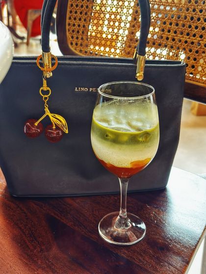 An aesthetic shot of a layered matcha latte next to a stylish handbag. This type of content captures a mood and is perfect for brands that align with a chic, modern, and calm lifestyle.
