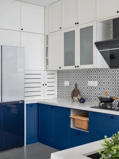 A full view of the 'Cover me in Sunshine' kitchen, where royal blue and white cabinets create a charming, patisserie-like feel. The design includes frosted glass shutters and sleek black hardware.