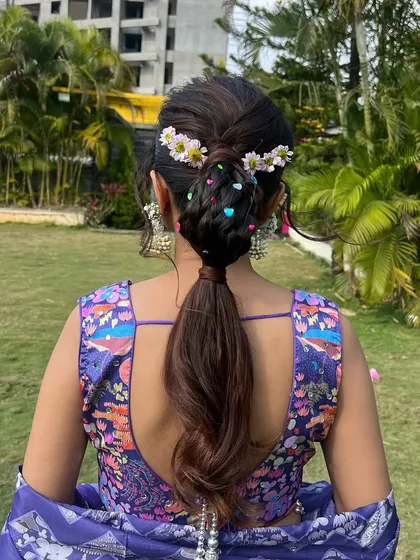 A back view of the whimsical braided ponytail, showing the combination of a bubble braid, flowers, and colorful heart beads.