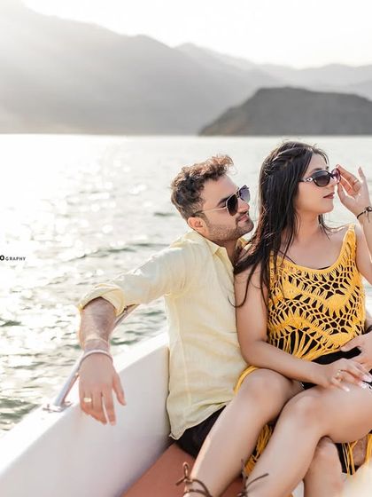 The couple enjoys the view from the boat, with the sun creating a beautiful flare. This kind of relaxed, scenic shot is a must-have for any lakeside pre-wedding session.