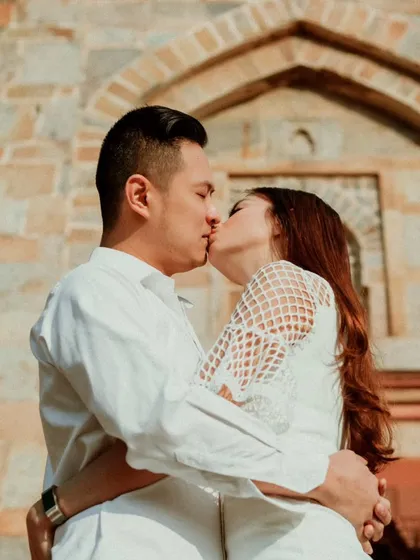 An intimate kiss in front of the historic stone architecture of Delhi. This destination pre-wedding shoot blends romance with the rich cultural heritage of the location.
