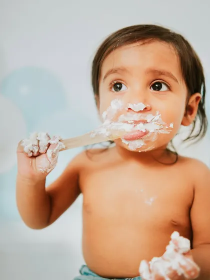Another delicious bite. The soft blue balloons in the background add a gentle pop of color to this minimalist cake smash setup.