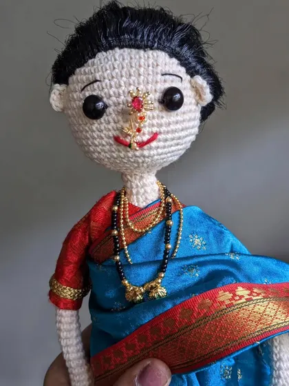 The doll held in hand, giving a sense of its personal, handmade quality.