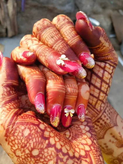 A classic bridal look perfect for the big day. I used gel extensions to create this elegant shape, combining a bold red gel polish with gold glitter accents and delicate 3D bows. This is the kind of glamorous wedding nail art I love creating for my brides.