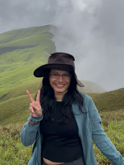 A happy trekker gives a peace sign, celebrating the stunning views and fresh mountain air at Netravathi.