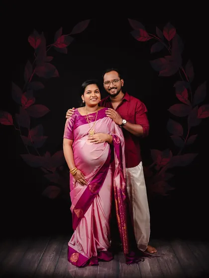 A beautiful, formal portrait celebrating South Indian tradition. The couple is dressed in a stunning pink silk saree and a classic veshti, creating a culturally rich and memorable maternity photograph.