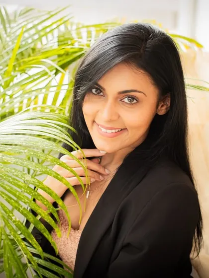 A confident smile framed by lush green leaves. This portrait blends natural elements with a classic pose.