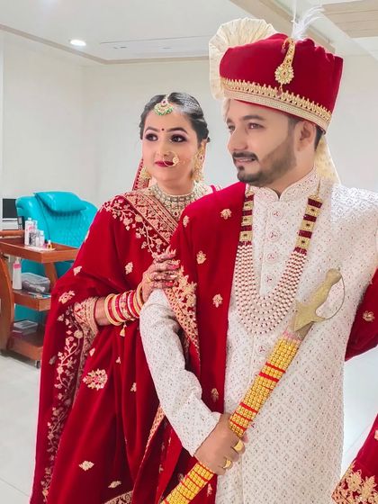 A candid moment between the bride and groom. Her makeup features a soft glam style that perfectly matches her red lehenga and his coordinated sherwani.