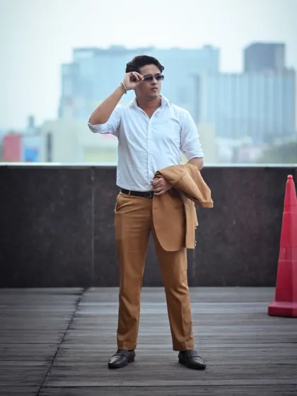 This shot has a candid feel, as if the subject is adjusting his sunglasses. It adds a touch of personality to a professional portfolio, showing confidence against the urban city background.