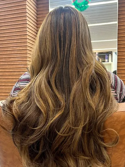 A gorgeous balayage with soft, natural-looking highlights. The hair is styled in loose waves, showing how the lighter pieces frame the face and add dimension without a drastic change.