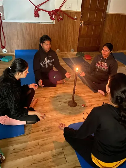 A small group focuses intently on the candle flame during Tratak. This practice is excellent for improving memory and cultivating a state of deep mindfulness.