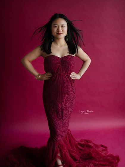 A confident and powerful pose. This full-length shot showcases the gorgeous maternity gown and the mother's radiant presence.