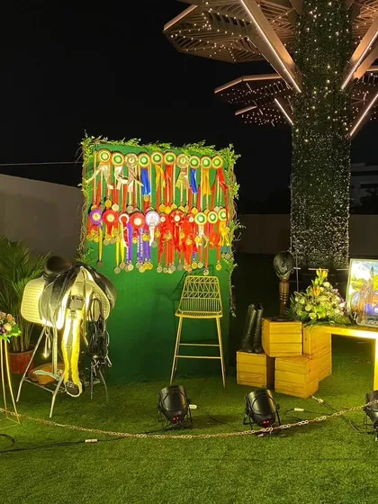 I design custom photo booths that fit the event's theme. For this equestrian champion's celebration, I created a themed corner with a saddle, riding gear, and a backdrop of her prize ribbons, making for a unique and personal photo spot.