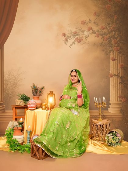 A full-length solo portrait showcasing a stunning green traditional dress. The backdrop with classic pillars and floral paintings adds a touch of royal elegance to the maternity photo.